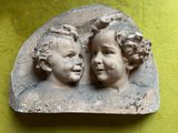 deux statues représentant deux enfants posées sur une surface verte