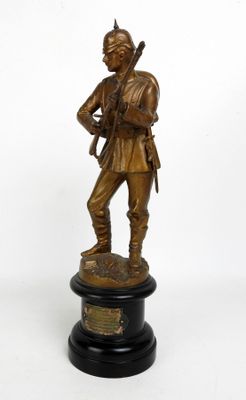 statue en bronze représentant un soldat tenant un fusil, posée sur un socle noir