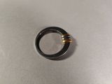 a black ring with two gold rings on top of it