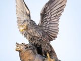 statue représentant un aigle et un ours sur un rocher, avec le ciel en arrière-plan