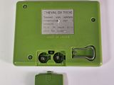 a small green device with a metal button on it