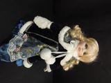 a doll with blonde hair and blue dress on a black surface