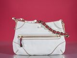 the white purse is sitting on a table with a red wall in the background