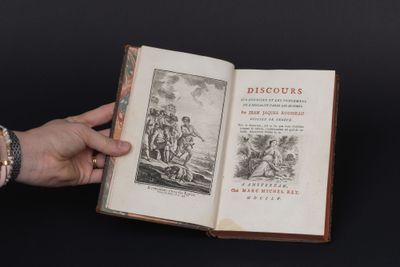 une personne tient un livre ouvert à la main sur un fond noir