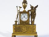 une horloge en or ornée d'anges et surmontée d'un vase