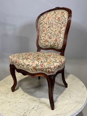 une image représentant une chaise dont l'assise est recouverte d'un tissu à motifs floraux, posée sur une table en marbre