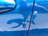 a reflection of a man in the side mirror of a blue car