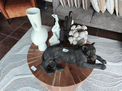 une statue représentant un chien couché sur une table, à côté d'un vase