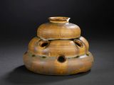 a brown vase with holes in it on a black surface