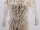 an antique white blouse on a mannequin stand with a white background