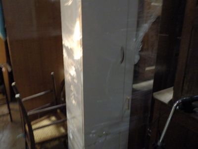 a tall white refrigerator sitting in a room with a chair