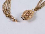 a close up of a gold necklace with a skull on it