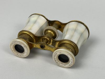 une paire de jumelles anciennes en laiton posées sur une surface blanche