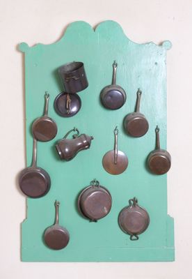 une photo d'une collection de casseroles et de poêles accrochées au mur