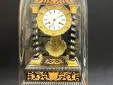 une horloge posée sur une table, sous un dôme en verre