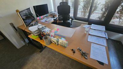 une photo d'un bureau sur lequel se trouvent deux ordinateurs et des papiers