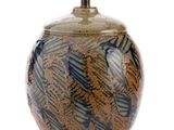un vase brun et bleu posé sur une surface blanche