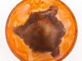 an overhead view of a glass of orange liquid on a white surface
