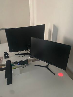 deux écrans posés sur un bureau, avec un clavier et une souris