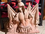 une statue représentant un homme assis sur une chaise, tenant une batte