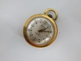 a gold pocket watch with a white face on a white surface