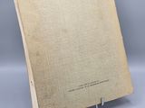 an old book sitting on top of a metal stand on a gray surface