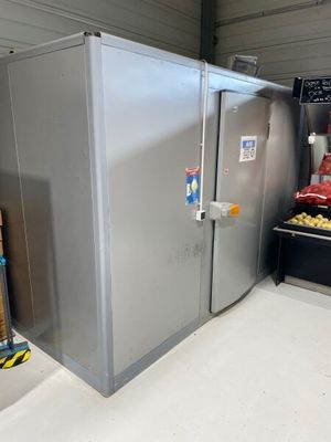 a silver refrigerator in the middle of a room next to a pile of food