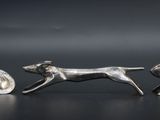 three silver figurines of animals running across a black surface