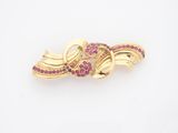 une image représentant une broche en or sertie de pierres roses sur fond blanc