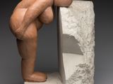 une image représentant une sculpture d'une personne appuyée contre un rocher