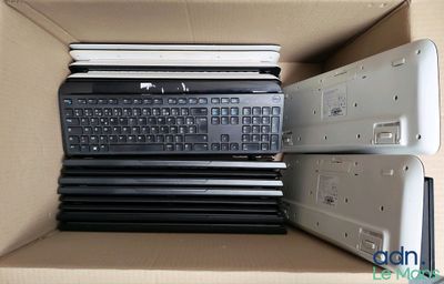 many laptops in a box with a keyboard on top of them