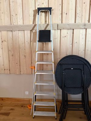 une échelle appuyée contre un mur, à côté d'une chaise