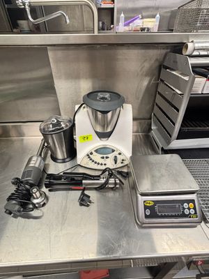 un plan de travail en acier inoxydable équipé d'un mixeur, d'une cafetière et d'autres appareils de cuisine
