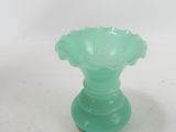 a green glass vase sitting on a white surface