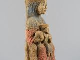 an old figurine of a woman sitting on a chair