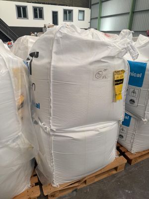 une grande pile de sacs blancs posée sur une palette dans un entrepôt