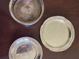 three silver plates sitting on top of a wooden table next to each other