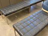two black leather benches and a blue chair in a room