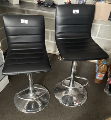 two black leather bar stools sitting on a counter