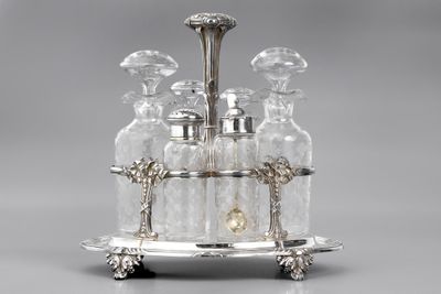 an antique silver plated liquor set with four bottles on a stand