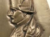 an image of a bronze medallion of a man wearing a hat