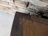 a cat sitting on a wooden bench in front of a stone wall