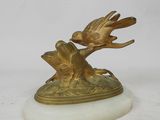 une statue en or représentant un oiseau, posée sur un socle en marbre