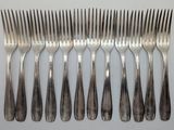 six forks and a knife are arranged in a row on a white surface