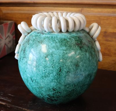 un vase vert contenant des coquillages blancs, posé sur une table