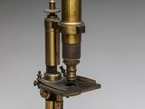 an antique brass microscope with a black base and a white background