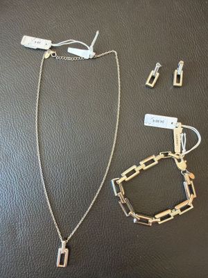 silver necklace and earring set on a black leather surface