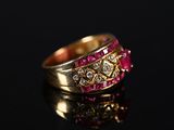 a close up of a gold ring with pink stones on a black surface