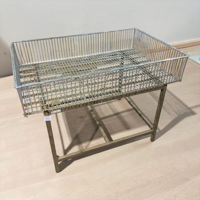 stainless steel wire basket on a metal stand on a wooden floor