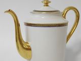a white and gold tea pot with a gold handle